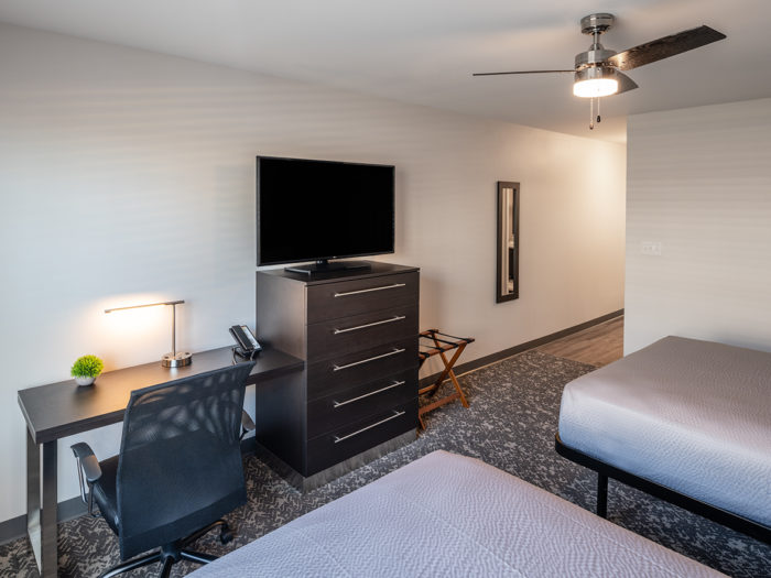 View of television, desk and two queen beds